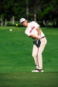 a man in white shirt and tan pants playing golf.