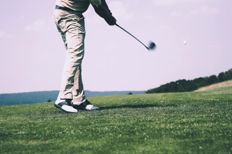 a man hitting a golf ball with a golf club.