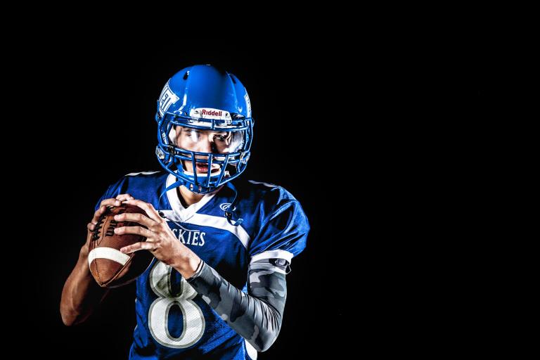 return-to-sport-football-high-ankle-sprain-768x512-1 - Scottsdale Physical Therapy & Performance - Scottsdale Physical Therapy & Performance a football player in a blue uniform holding a ball.