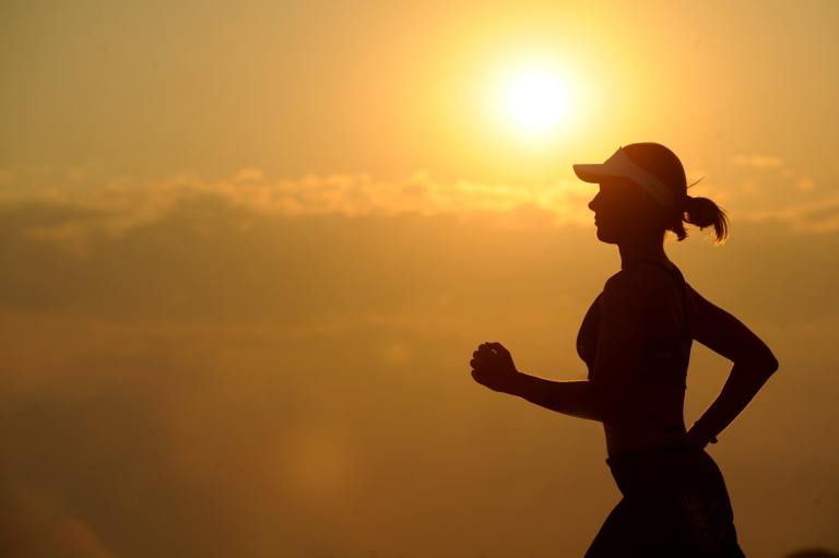 a silhouette of a woman running at sunset.
