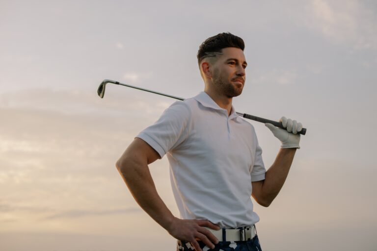 a man holding a golf club and wearing a white shirt.