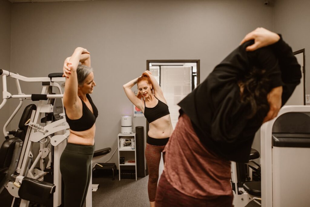 two women in a gym doing exercises in front of a mirror.