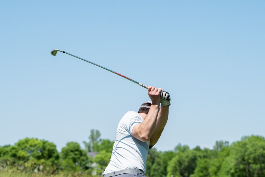 a man swinging a golf club on a sunny day.