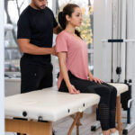 Physical therapist evaluating a woman's lower back and posture during a sciatica treatment session