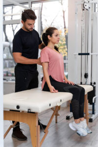 Physical therapist evaluating a woman's lower back and posture during a sciatica treatment session