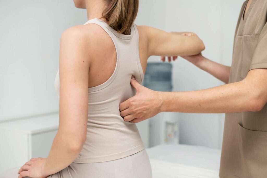 Physiotherapist assisting a woman with shoulder and back mobility assessment during a physical therapy session