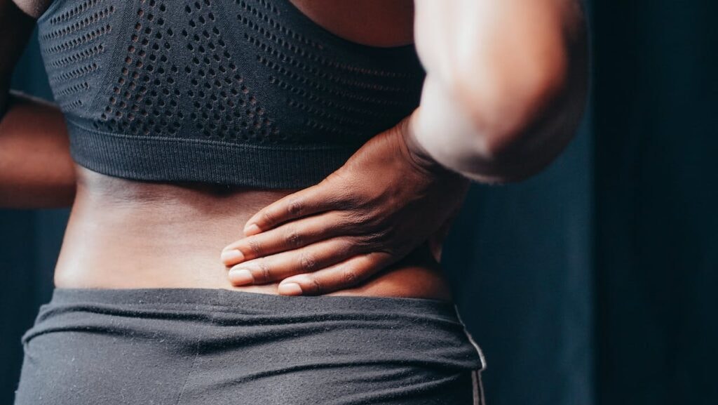 Person holding their lower back in pain, a common symptom that trapped nerve lower back exercises may help relieve.