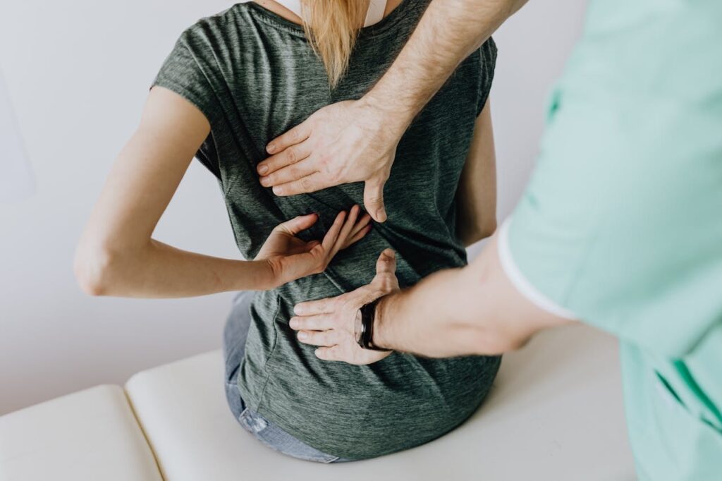 Physical therapist palpating the thoracic area during an evaluation for upper middle back pain when breathing.