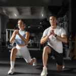 Two people performing lunges in a gym, training physical fitness components health related for better strength and movement control