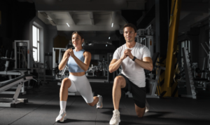 Two people performing lunges in a gym, training physical fitness components health related for better strength and movement control