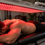 Athlete receiving red light therapy for muscle recovery in a modern physical therapy clinic