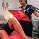 Physical therapist applying red light therapy for knee pain during a clinic session