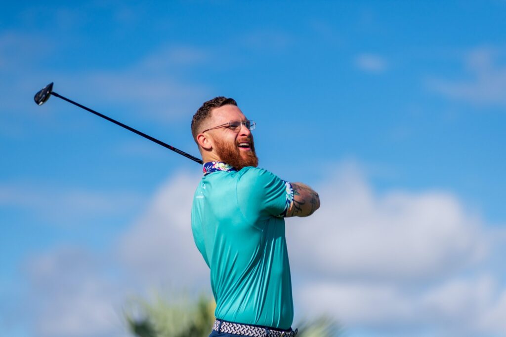 a man swinging a golf club on a sunny day.